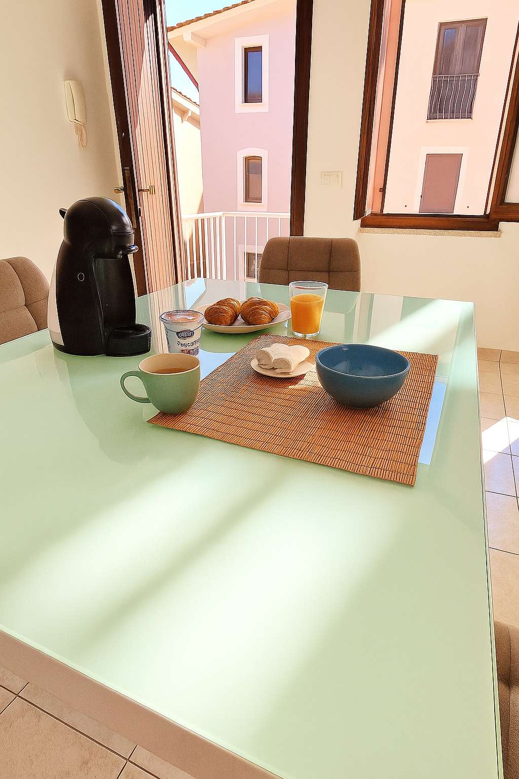 Frühstück auf dem Wohnzimmertisch mit Croissants, Orangensaft, Tassen und Kaffeemaschine